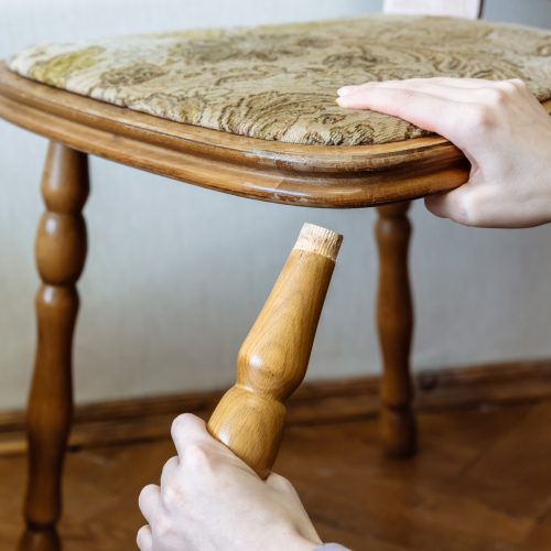 Broken chair. Woman is holding it in hands. Old furniture.